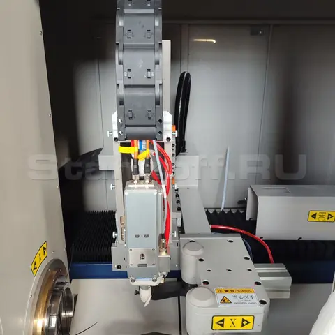 Лазерная режущая голова c автофокусом Ospri LC40. Под лазерной головой расположен пневмозахват для вытягивания трубы из зоны погрузки и её удержания в момент раскроя.